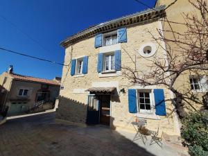 L'angélus, gîte de charme au coeur du vieux village de Sablet في Sablet: مبنى حجري كبير عليه مصاريع زرقاء