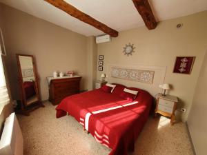 L'angélus, gîte de charme au coeur du vieux village de Sablet في Sablet: غرفة نوم بسرير احمر ومرآة
