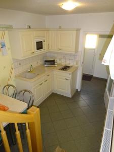 a kitchen with white cabinets and a sink and a table at Ferienwohnung Pension Sigwarth in Belgern