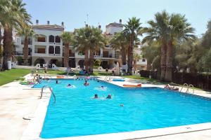 a group of people in a swimming pool with palm trees at Apartment on the Plaza in Villamartin