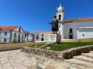 uma estátua de um homem parado em frente a um edifício em Maré Alta em Sines