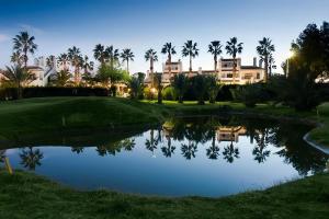 a view of a golf course with palm trees and a pond at Apartment on the Plaza in Villamartin
