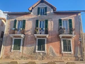 an old building with green shuttered windows and balconies at Mamma-Mia in Calvi