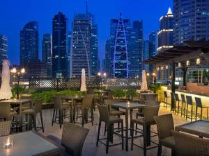 Armada Avenue Hotel - formerly Armada BlueBay Hotel في دبي: فناء على السطح مع طاولات وكراسي وأفق المدينة