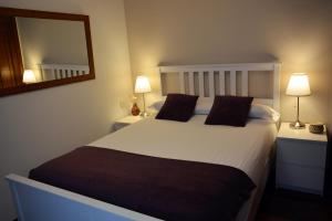1 dormitorio con 1 cama blanca grande y espejo en Santiago Apartment en Santiago de Compostela