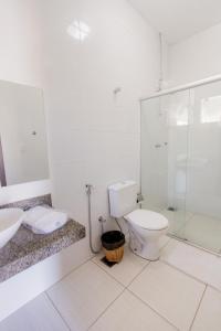 a bathroom with a toilet and a glass shower at Pousada Pontal in Curvelo