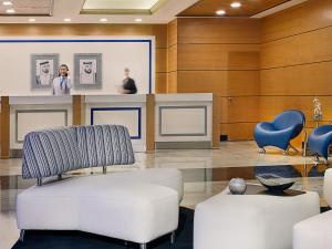a lobby with a white couch and chairs and a counter at Armada Avenue Hotel - formerly Armada BlueBay Hotel in Dubai