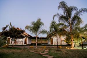 een huis met palmbomen ervoor bij Pousada Pontal in Curvelo