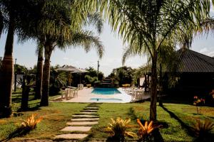 a backyard with a pool and palm trees at Pousada Pontal in Curvelo