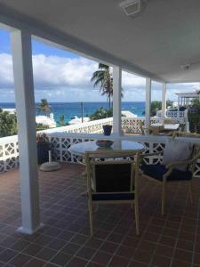 a patio with a table and chairs and the ocean at Bermuda At the Beach One-Bedroom in Paget Parish