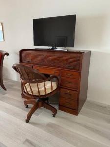 a wooden desk with a television and a chair at Bermuda At the Beach One-Bedroom in Paget Parish