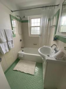 a white bathroom with a tub and a sink at Bermuda At the Beach One-Bedroom in Paget Parish