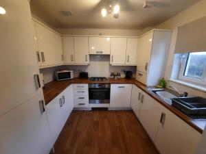 una cucina con armadi bianchi e lavandino di Pond View Upper ad Airdrie