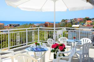 a balcony with tables and chairs and an umbrella at Hotel TRIADA in Limenaria