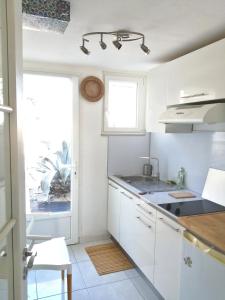 een keuken met witte kasten, een wastafel en een raam bij Majopau in Boujan-sur-Libron