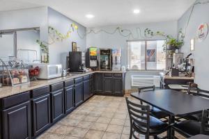 a kitchen with black cabinets and a table at Super 8 by Wyndham Kokomo in Kokomo
