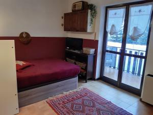 1 dormitorio con cama roja y balcón en Appartamento arredato con angolo cottura, en Argentera
