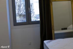 ein Schlafzimmer mit einem Spiegel und einem Fenster in der Unterkunft Bon'appart in Ajaccio