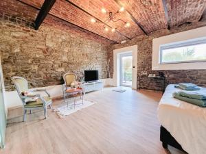 a brick walled bedroom with a bed and a desk and chairs at Au bout de mes rêves in Walcourt