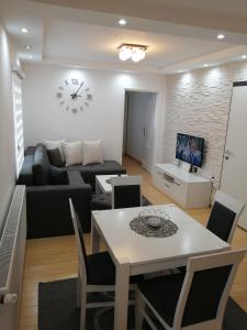 sala de estar con sofá, mesa y reloj en Apartments NS Novaković, en Zlatibor