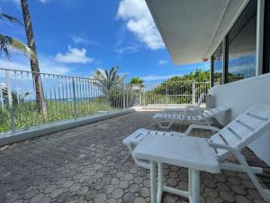 un patio con sillas blancas y un balcón con vistas al océano. en Studio BTS - Lauderdale-By-The-Sea, en Pompano Beach
