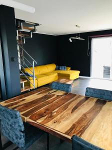 a dining room with a wooden table and a yellow couch at Baltic Sea Home in Jastrzębia Góra