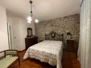 ein Schlafzimmer mit einem Bett und einer Steinwand in der Unterkunft Bellissima casa dentro il castello di San Savino in San Savino