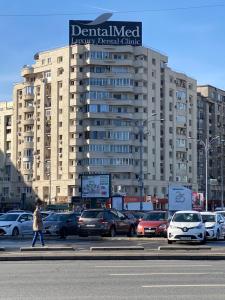 een groot gebouw met auto's geparkeerd op een parkeerplaats bij VICTORIEI by GREEN APARTMENTS in Boekarest