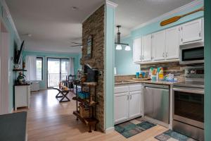 a kitchen with white cabinets and a stone wall at The Rustic Anchor in Hilton Head Island