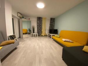 een woonkamer met een gele bank en een televisie bij VICTORIEI by GREEN APARTMENTS in Boekarest