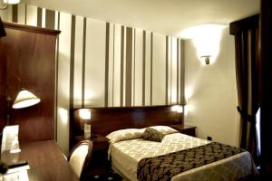 キアラモンテ・グルフィにあるAntica Stazioneのベッド、テーブル、ランプが備わるホテルルームです。