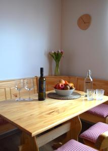 a wooden table with a bowl of fruit and wine glasses at Apartmány Réví in Hlohovec