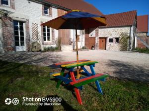 a picnic table with an umbrella in a yard at Chez Maman in Beugnon