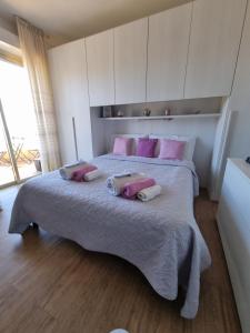 ein Schlafzimmer mit einem großen Bett mit rosa Kissen in der Unterkunft Il Paradiso del Relax Chambres d'hotes Affittacamere room with sea view in Sanremo
