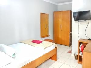 a small bedroom with a bed and a tv at Griya Sakina Syariah near JIH Yogyakarta Mitra RedDoorz in Kejayan