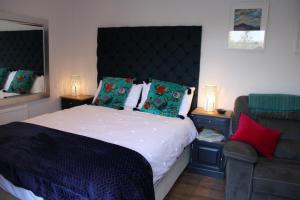 a bedroom with a large bed and a chair at The Nook @ Applemede in Chudleigh