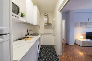 a kitchen with white cabinets and a tv on the wall at Apartamento Albelda Plaza in Albelda de Iregua