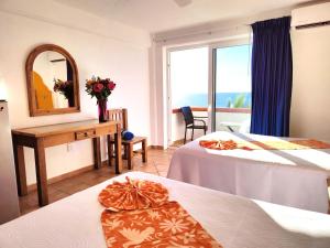 a hotel room with two beds and a mirror at Hotel El Pescador in Puerto Vallarta