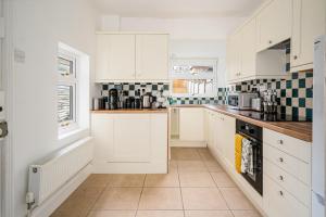 a kitchen with white cabinets and a tile floor at Fantastic, Spacious 3 Bedroom House With Garden in Bath