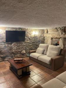 a living room with a couch and a tv on a stone wall at Casa da Aldeia in Azevo