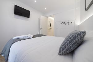 a white bedroom with a bed and a flat screen tv at Apartamento Logroño Avenida Ayuntamiento in Logroño