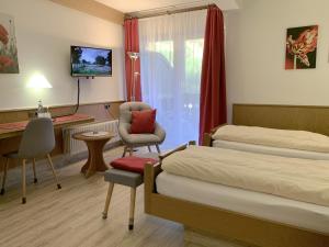 ein Hotelzimmer mit 2 Betten, einem Stuhl und einem Schreibtisch in der Unterkunft Landhotel Untere Kapfenhardter Mühle in Unterreichenbach