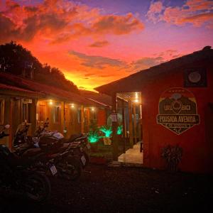 eine Gruppe von Motorrädern, die vor einem Gebäude mit Sonnenuntergang geparkt sind in der Unterkunft Pousada avenida in Urubici