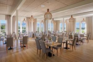 a dining room with tables and chairs and windows at Hotel Hamar in Borgarnes
