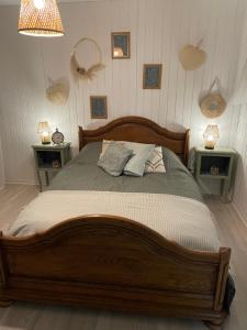 ein Schlafzimmer mit einem großen Holzbett mit zwei Tischen in der Unterkunft Les Hortensias de Marie in Laviéville