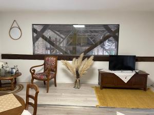 ein Wohnzimmer mit einem TV, einem Tisch und Stühlen in der Unterkunft Les Hortensias de Marie in Laviéville