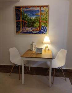 アテネにあるKolonaki Elegant apartmentのテーブル(椅子2脚、ランプ1脚、絵画1点)
