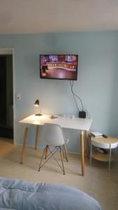 Habitación con escritorio y TV en la pared. en Arbois, joli petit appartement plein centre, en Arbois