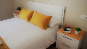 a bedroom with a white bed with yellow pillows and a table at ***** Solaina das Burgas ***** en el Casco Viejo in Ourense