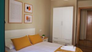 een slaapkamer met een bed met witte lakens en oranje kussens bij ***** Solaina das Burgas ***** en el Casco Viejo in Ourense